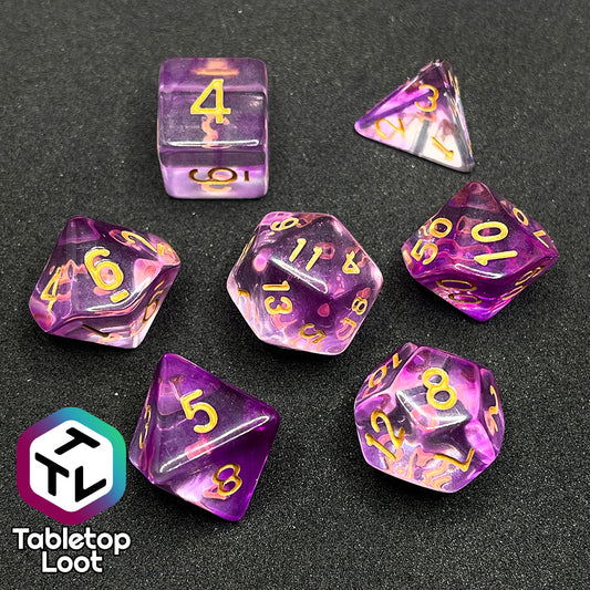 The Incantation 7 piece dice set from Tabletop Loot with swirls of fuchsia in clear and gold numbering.
