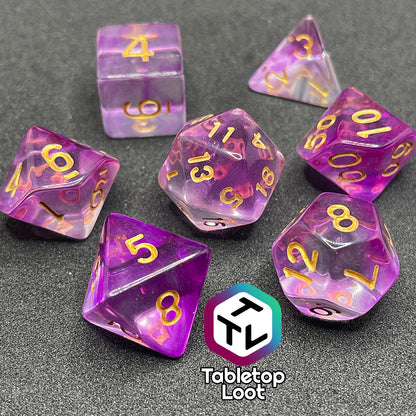 The Incantation 7 piece dice set from Tabletop Loot with swirls of fuchsia in clear and gold numbering.