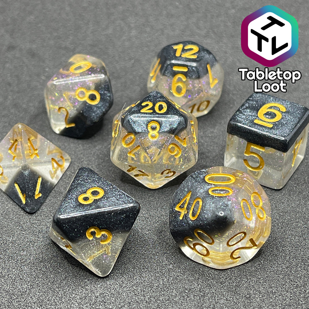 The Inkwell 7 piece dice set from Tabletop Loot with a layer of black glittery color on clear glittery resin and gold numbering.