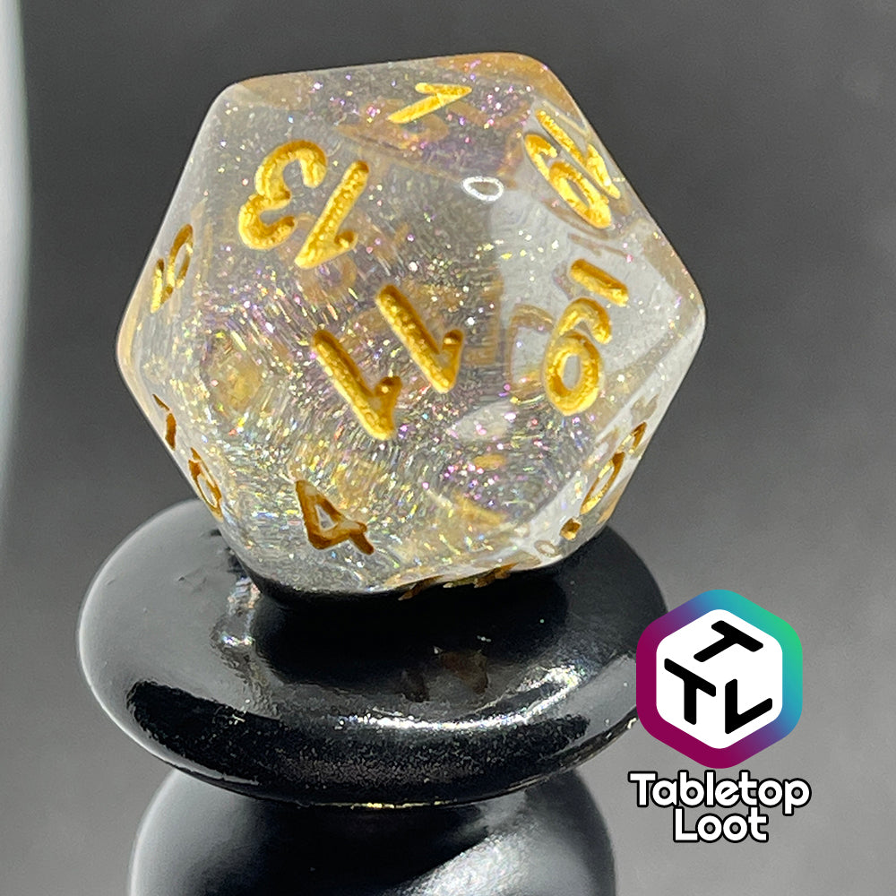 A close up of the D20 from the Inkwell 7 piece dice set from Tabletop Loot with a layer of black glittery color under clear glittery resin and gold numbering.