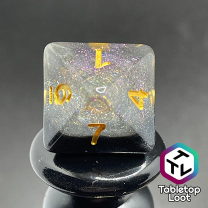 A close up of the D8 from the Inkwell 7 piece dice set from Tabletop Loot with a layer of black glittery color under clear glittery resin and gold numbering.