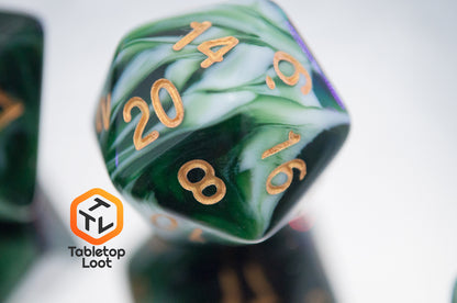 A close up of the Jadeite Cabbage 7 piece dice set from Tabletop Loot with swirls of shades of green and white, numbered in gold.