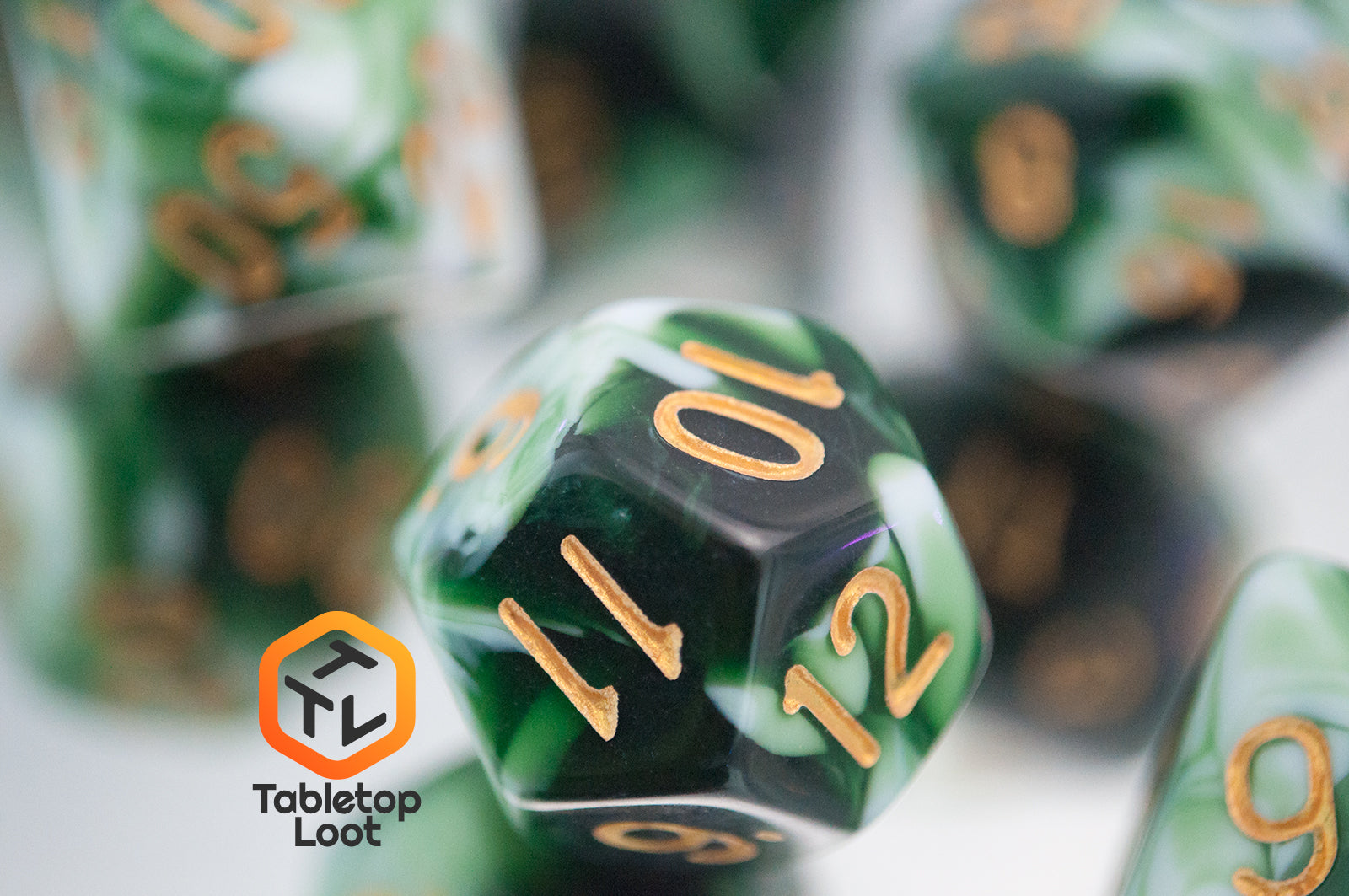 A close up of the D12 from the Jadeite Cabbage 7 piece dice set from Tabletop Loot with swirls of shades of green and white, numbered in gold.