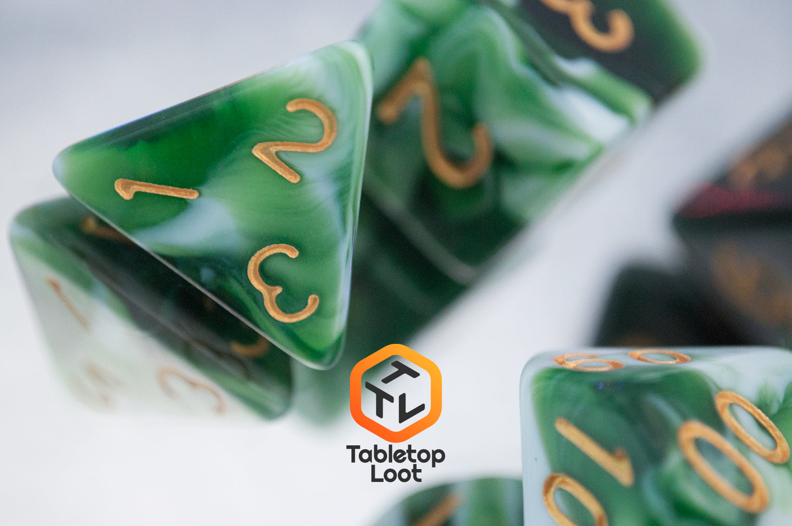 A close up of the D4 from the Jadeite Cabbage 7 piece dice set from Tabletop Loot with swirls of shades of green and white, numbered in gold.