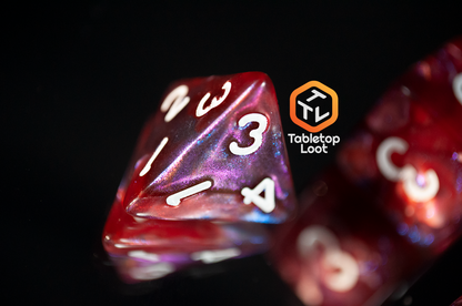 A close up of the D4 from the Lava Galaxy 7 piece dice set from Tabletop Loot with swirls of red, blue, and purple with tons of shimmer and white numbers.
