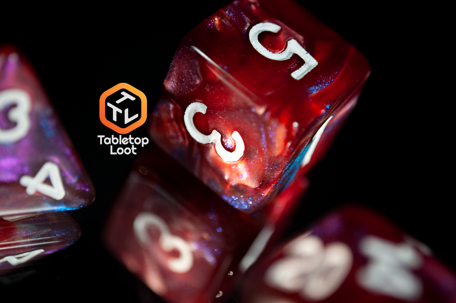 A close up of the D6 from the Lava Galaxy 7 piece dice set from Tabletop Loot with swirls of red, blue, and purple with tons of shimmer and white numbers.