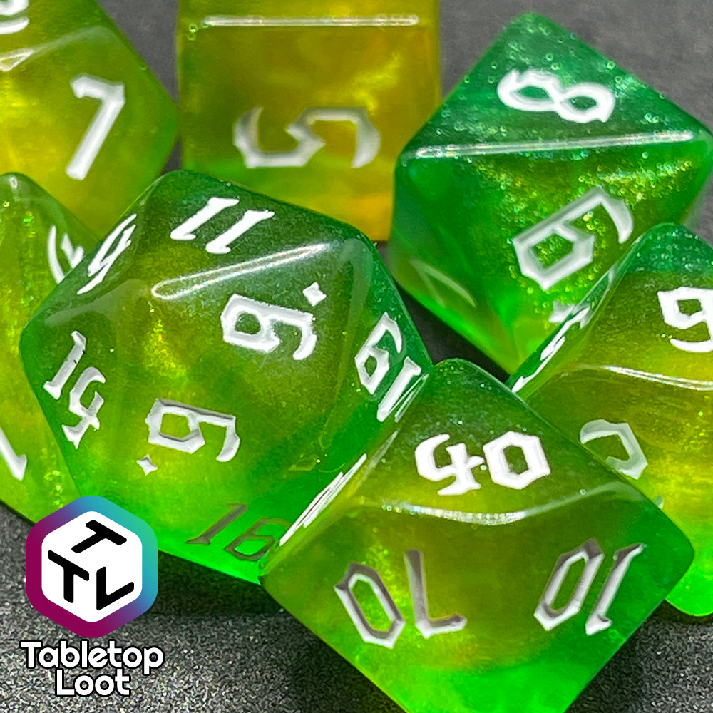 A close up of the Luck 7 piece dice set from Tabletop Loot; translucent green and yellow swirled with micro glitter and white gothic numbering.