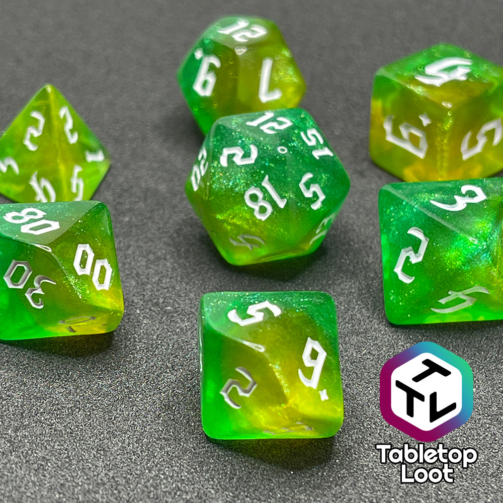 A close up of the Luck 7 piece dice set from Tabletop Loot; translucent green and yellow swirled with micro glitter and white gothic numbering.