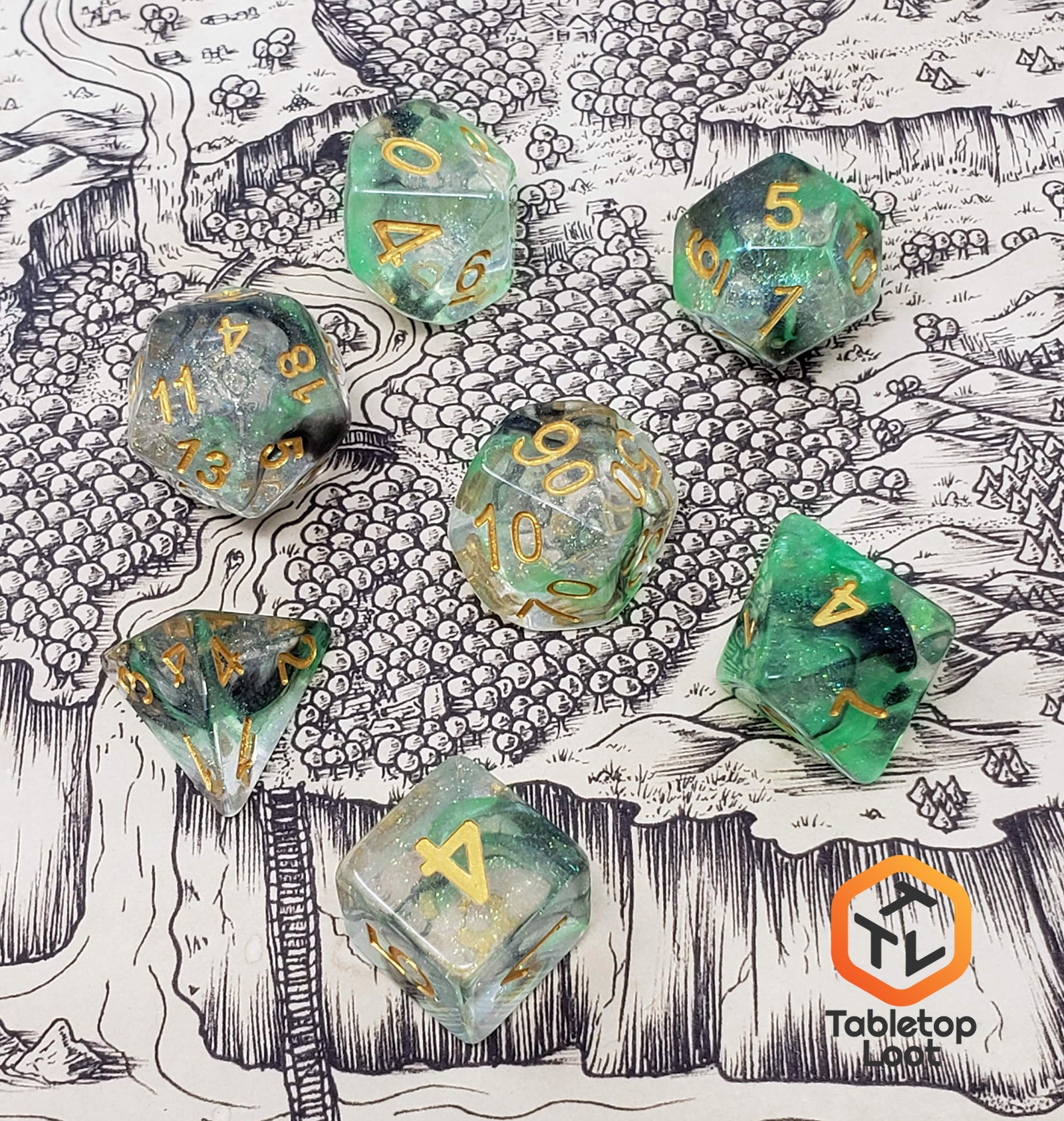 The Luminous Venom 7 piece dice set from Tabletop Loot with green and black swirls in a clear glittery resin with gold numbering on a map by Deven Rue.