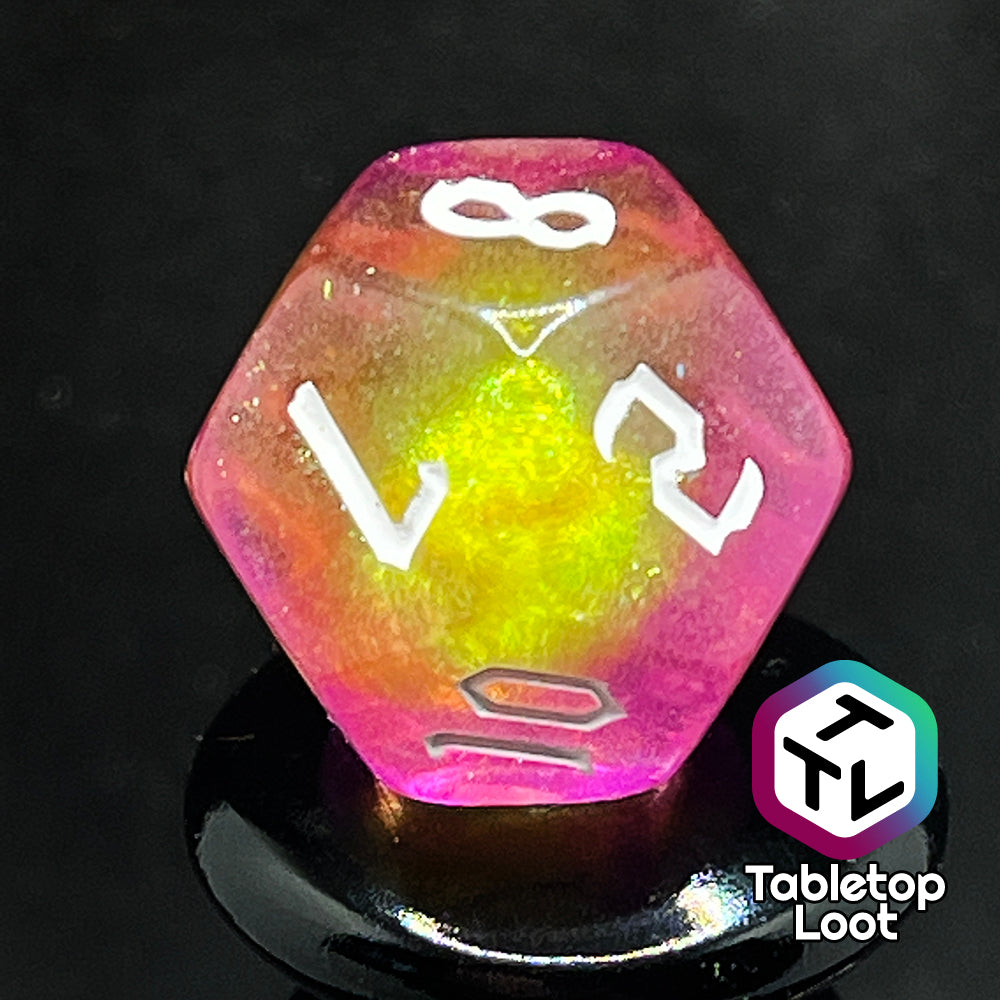 A close up of the D12 from the Lunar Tides 7 piece dice set from Tabletop Loot swirling with pink and yellow, packed with glitter, and with white gothic numbering.