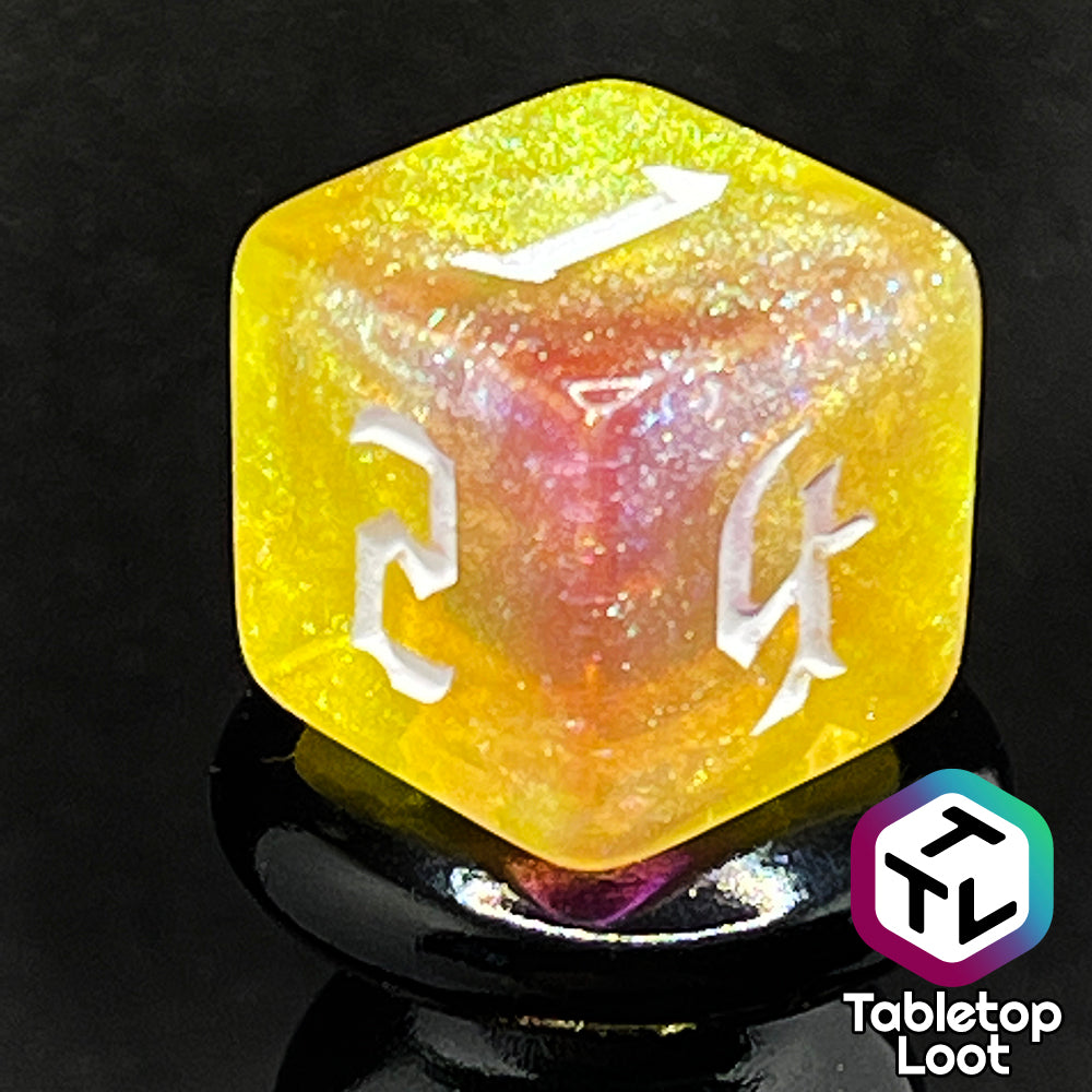 A close up of the D6 from the Lunar Tides 7 piece dice set from Tabletop Loot swirling with pink and yellow, packed with glitter, and with white gothic numbering.