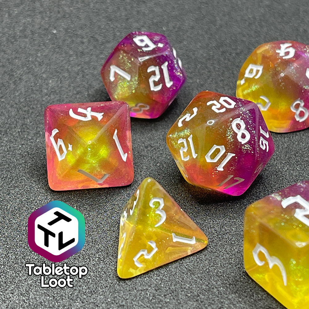 A close up of the Lunar Tides 7 piece dice set from Tabletop Loot swirling with pink and yellow, packed with glitter, and with white gothic numbering.