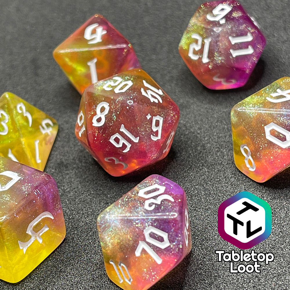 A close up of the Lunar Tides 7 piece dice set from Tabletop Loot swirling with pink and yellow, packed with glitter, and with white gothic numbering.