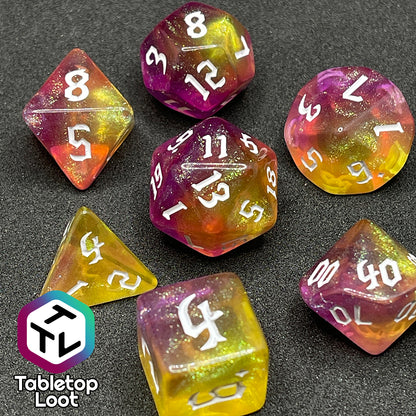 The Lunar Tides 7 piece dice set from Tabletop Loot swirling with pink and yellow, packed with glitter, and with white gothic numbering.