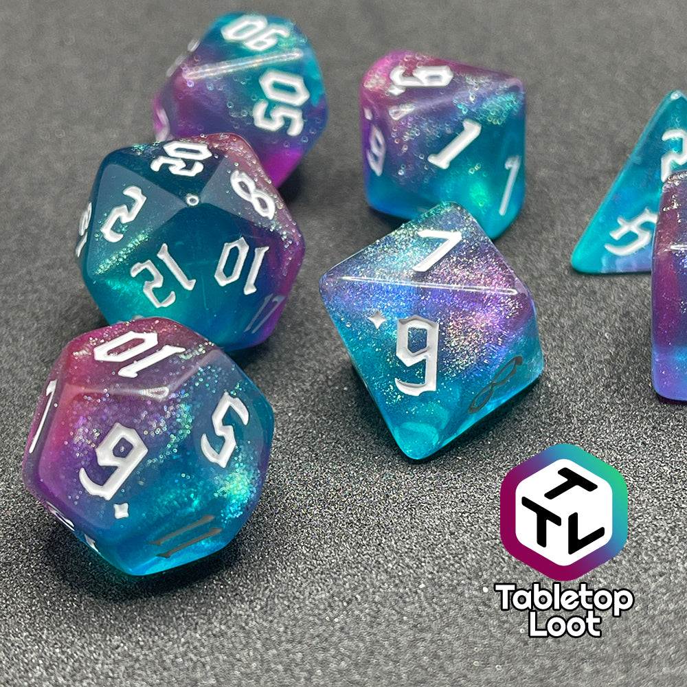 A close up of the Mermaid Lagoon 7 piece dice set from Tabletop Loot with shimmery swirls of blue and purple and white gothic numbering.
