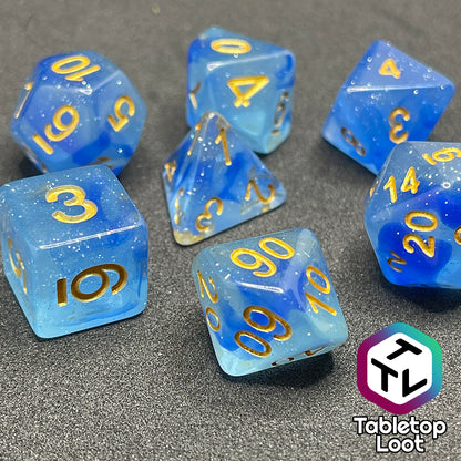 The Mermaid's Crown 7 piece dice set from Tabletop Loot with swirled blue tones, tons of glitter, and gold numbering.