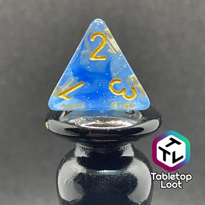 A close up of the D4 from the Mermaid's Crown 7 piece dice set from Tabletop Loot with swirled blue tones, tons of glitter, and gold numbering.