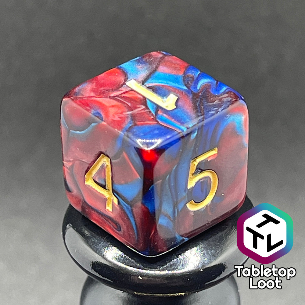 A close up of the D6 from the Metropolis 11 piece dice set from Tabletop Loot with swirls of red and blue and gold numbering.