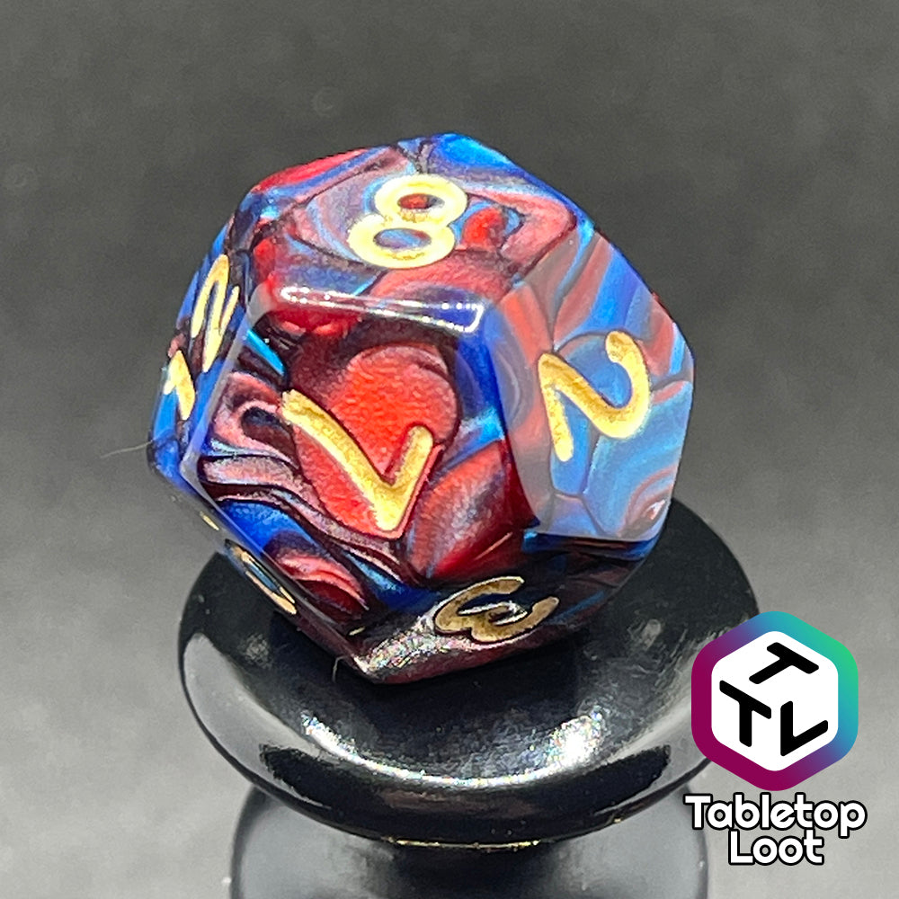 A close up of the D12 from the Metropolis 11 piece dice set from Tabletop Loot with swirls of red and blue and gold numbering.