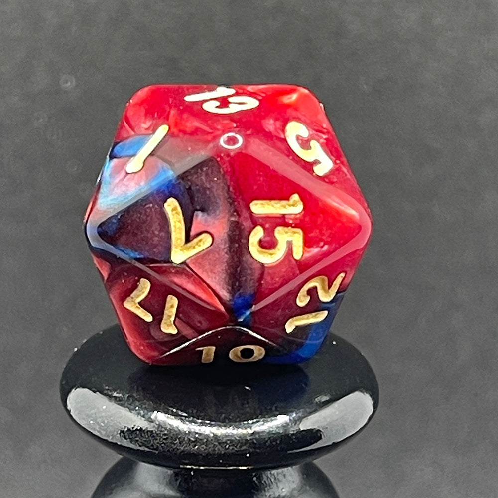 A close up of the D20 from the Metropolis 7 piece dice set with swirls of pearlescent blue and red and gold numbering.