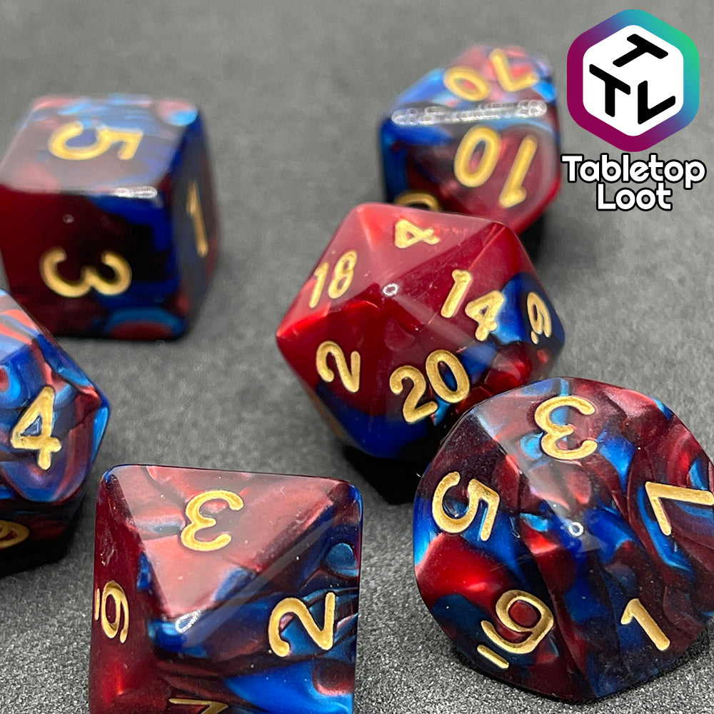 A close up of the Metropolis 7 piece dice set with swirls of pearlescent blue and red and gold numbering.