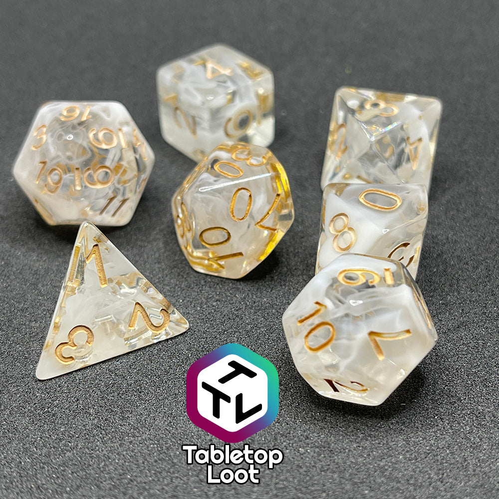 The Mists of Avalon 7 piece dice set from Tabletop Loot; clear with swirls of white and gold numbering.