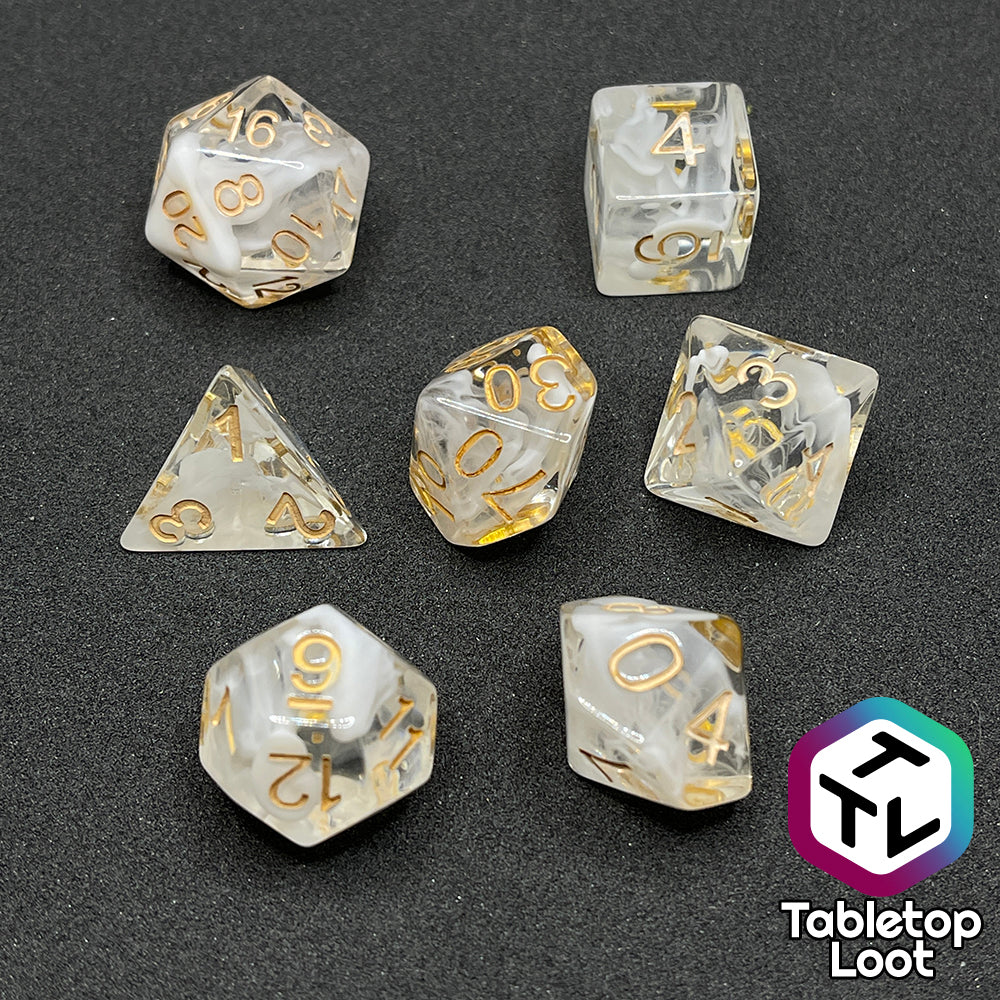 The Mists of Avalon 7 piece dice set from Tabletop Loot; clear with swirls of white and gold numbering.