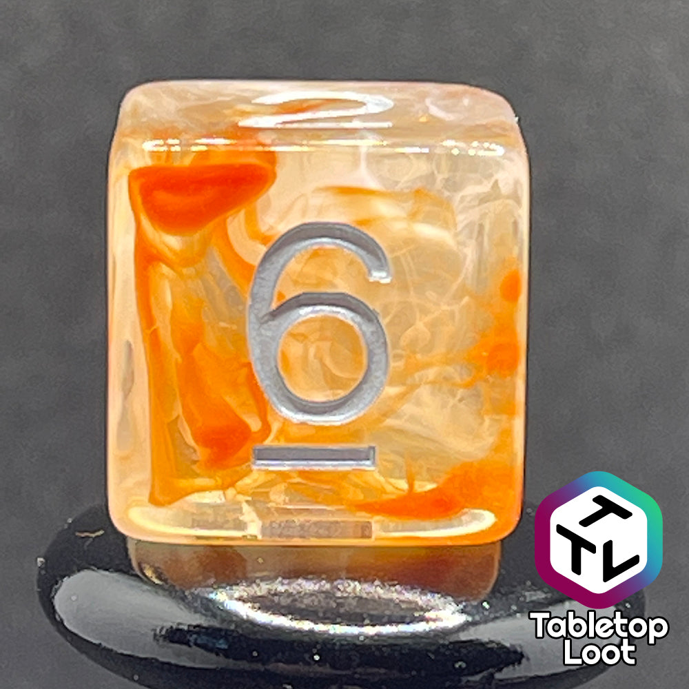 A close up of the D6 from the Hunter's Moon 7 piece dice set from Tabletop Loot with swirls of orange and white in clear resin and white numbering.
