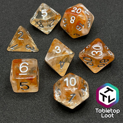 The Hunter's Moon 7 piece dice set from Tabletop Loot with swirls of orange and white in clear resin and white numbering.