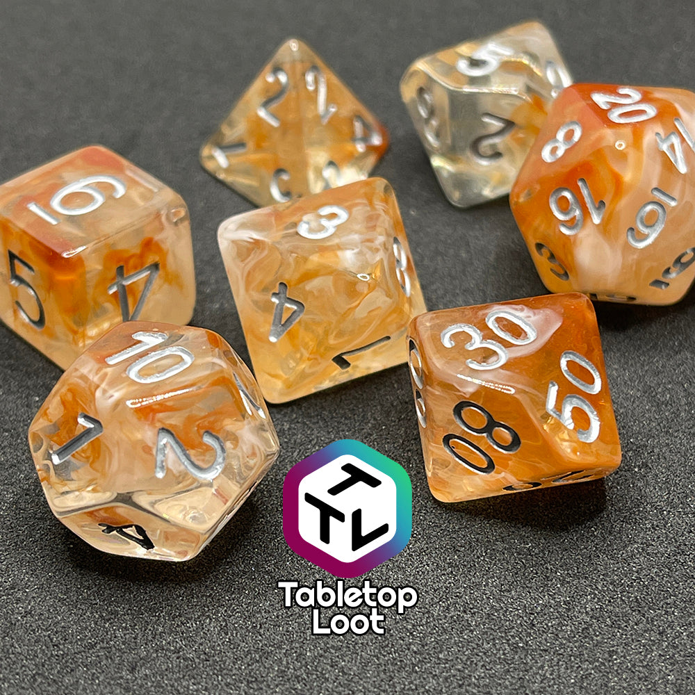 A close up of the Hunter's Moon 7 piece dice set from Tabletop Loot with swirls of orange and white in clear resin and white numbering.