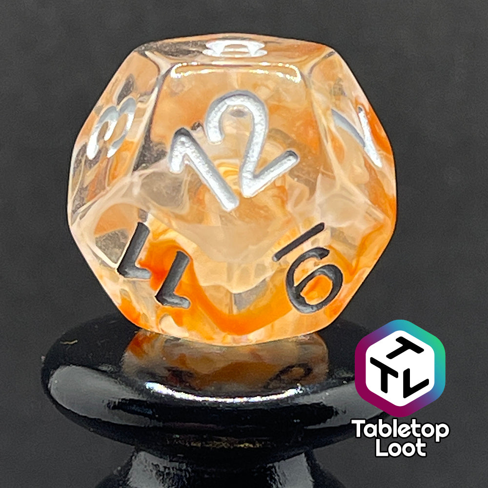 A close up of the D12 from the Hunter's Moon 7 piece dice set from Tabletop Loot with swirls of orange and white in clear resin and white numbering.