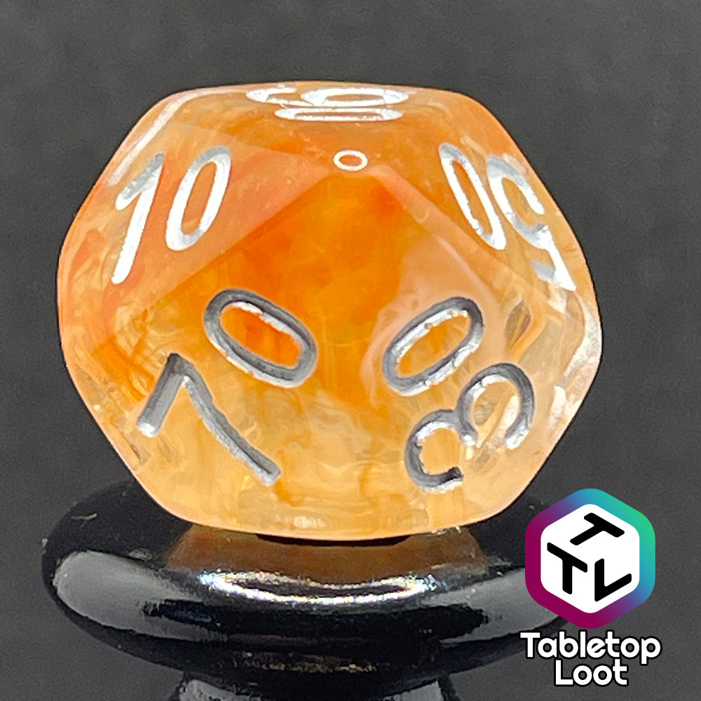 A close up of the percentile die from the Hunter's Moon 7 piece dice set from Tabletop Loot with swirls of orange and white in clear resin and white numbering.