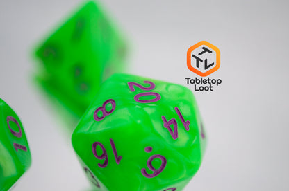 A close up of the D20 from the Radioactive Green 7 piece dice set from Tabletop Loot with bright green resin and purple numbering.
