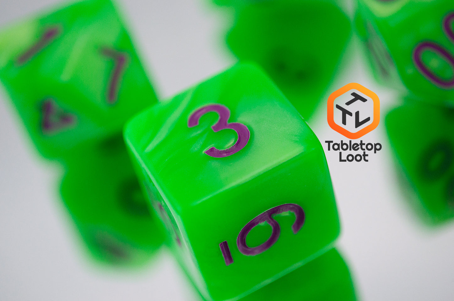 A close up of the D6 from the Radioactive Green 7 piece dice set from Tabletop Loot with bright green resin and purple numbering.