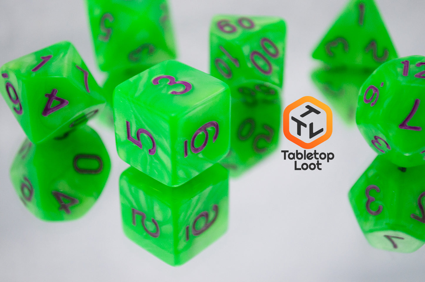 A close up of the Radioactive Green 7 piece dice set from Tabletop Loot with bright green resin and purple numbering.