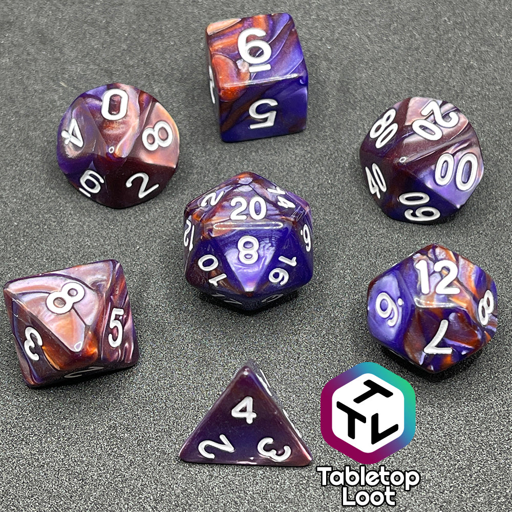 The Mystical Aura 7 piece dice set from Tabletop Loot with swirls of iridescent blue, purple, and orange and white numbering.