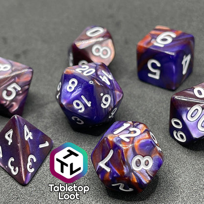 The Mystical Aura 7 piece dice set from Tabletop Loot with swirls of iridescent blue, purple, and orange and white numbering.