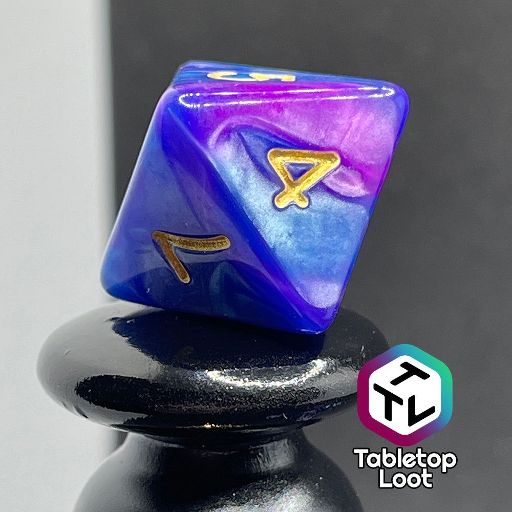 A close up of the D8 from the Mystique 7 piece dice set from Tabletop Loot with swirls of purple in pearlescent blue and gold numbering.