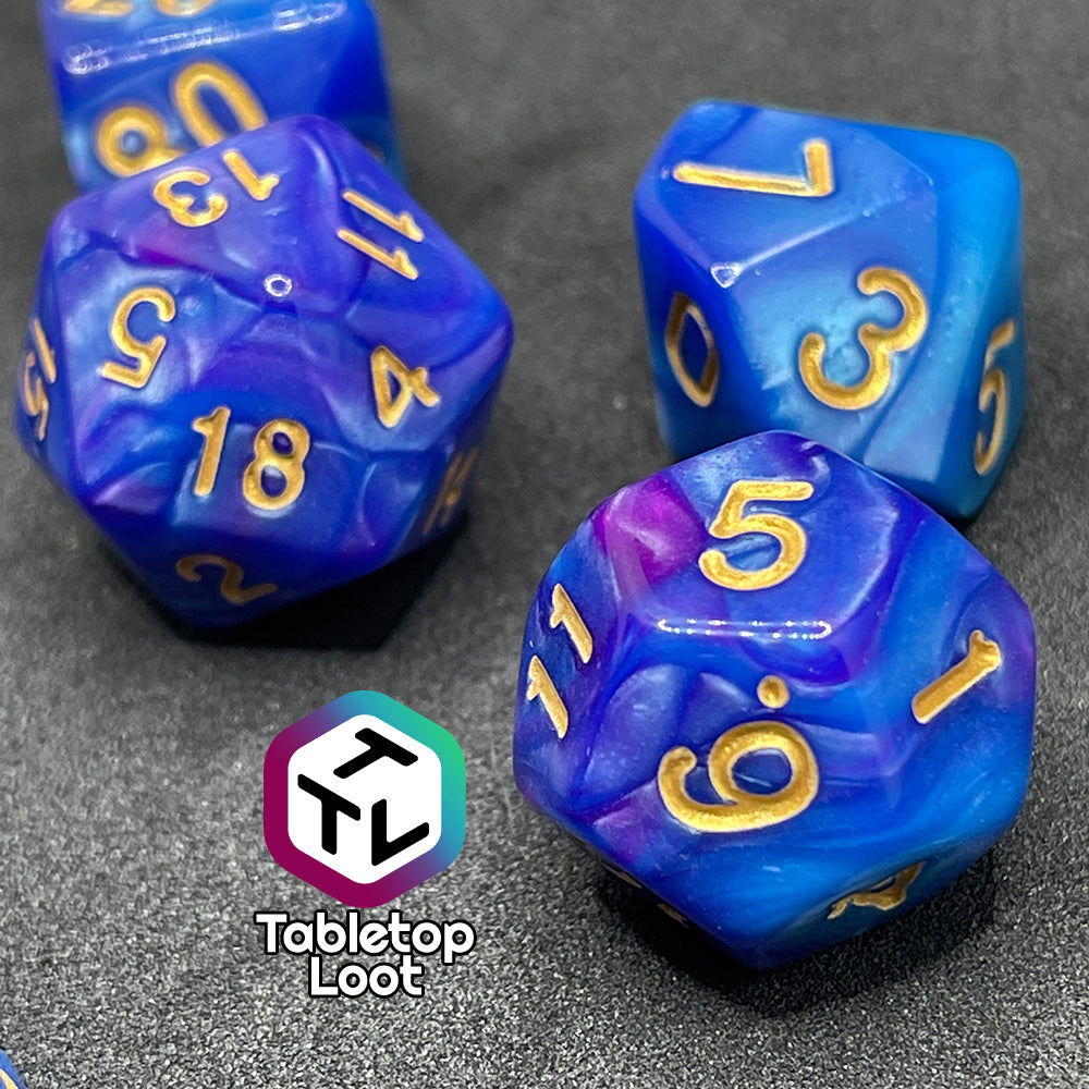 A close up of the Mystique 7 piece dice set from Tabletop Loot with swirls of purple in pearlescent blue and gold numbering.
