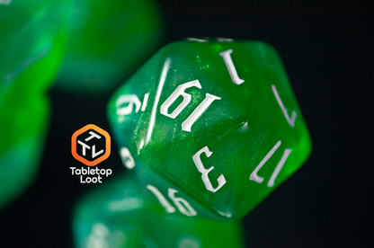 A close up of the D20 from the Nature's Fury 7 piece dice set from Tabletop Loot with shimmering translucent green resin and white numbering.