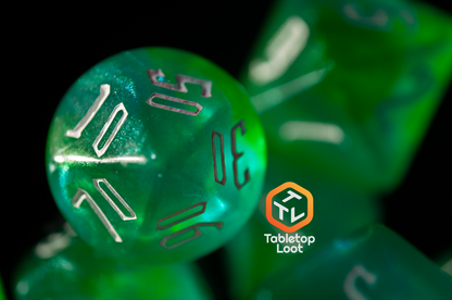 A close up of the percentile die from the Nature's Fury 7 piece dice set from Tabletop Loot with shimmering translucent green resin and white numbering.