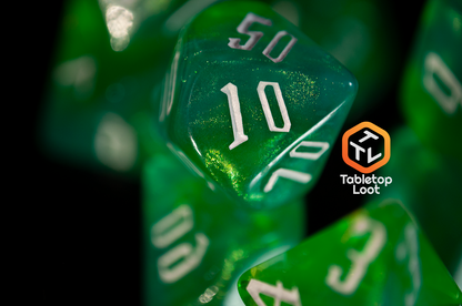 A close up of the Nature's Fury 7 piece dice set from Tabletop Loot with shimmering translucent green resin and white numbering.