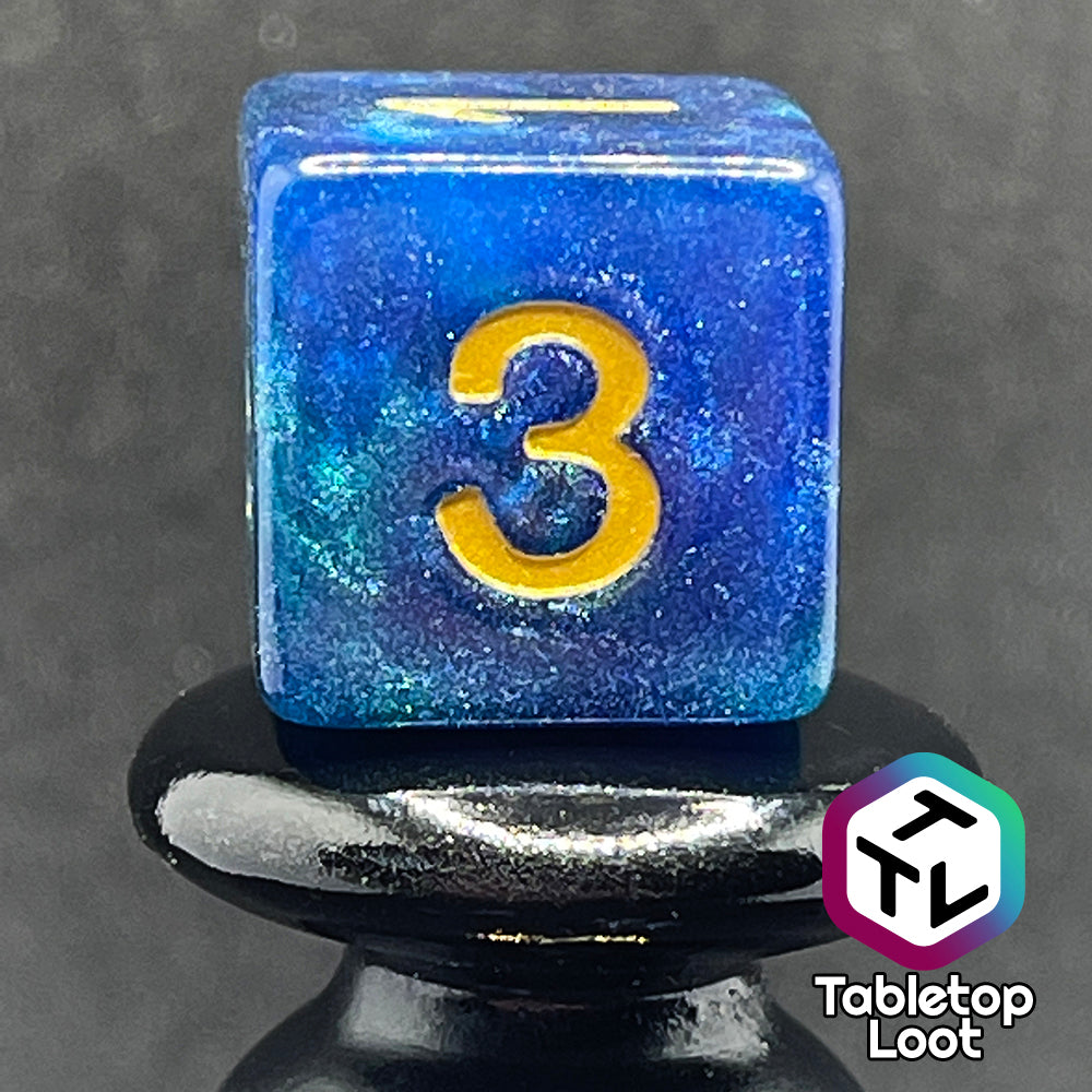A close up of the D6 from the Neptune's Grace 7 piece dice set from Tabletop Loot with swirls of shimmery blue, hints of green , and gold numbering.