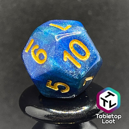 A close up of the D12 from the Neptune's Grace 7 piece dice set from Tabletop Loot with swirls of shimmery blue, hints of green , and gold numbering.