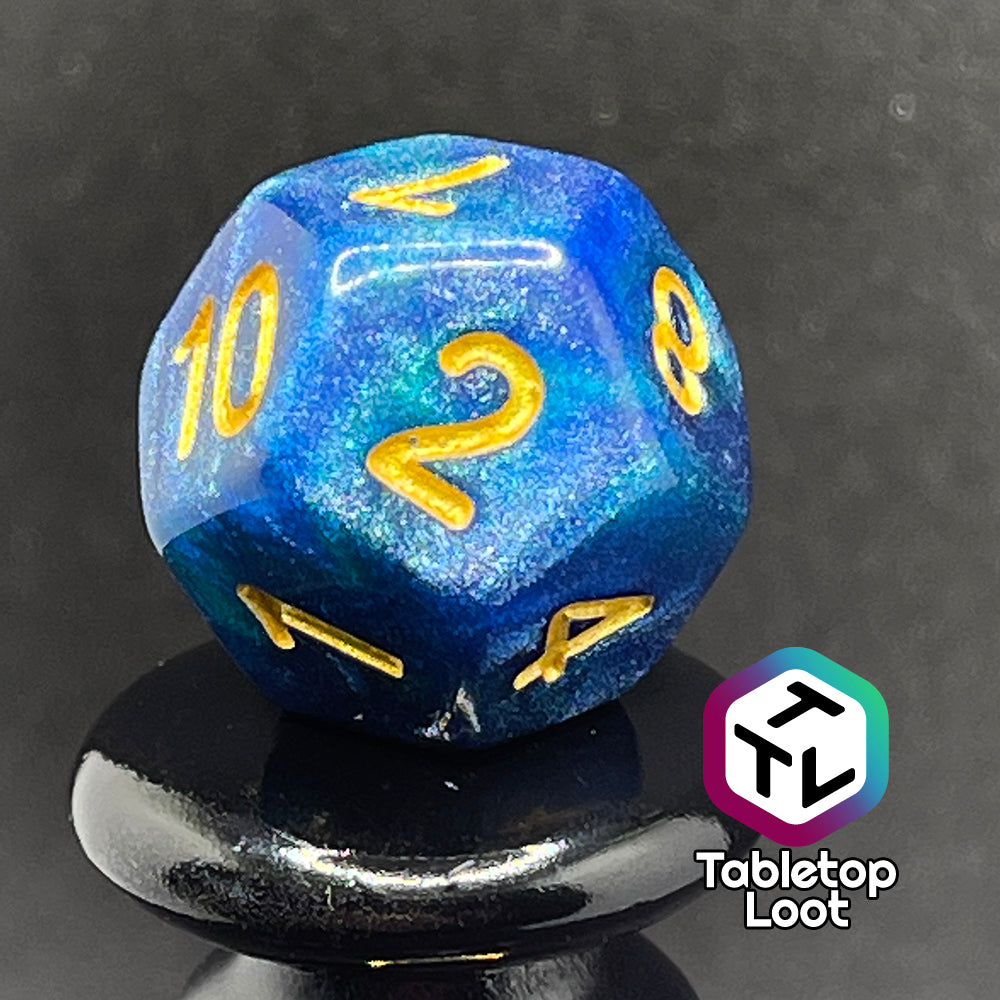 A close up of the D12 from the Neptune's Grace 7 piece dice set from Tabletop Loot with swirls of shimmery blue, hints of green , and gold numbering.