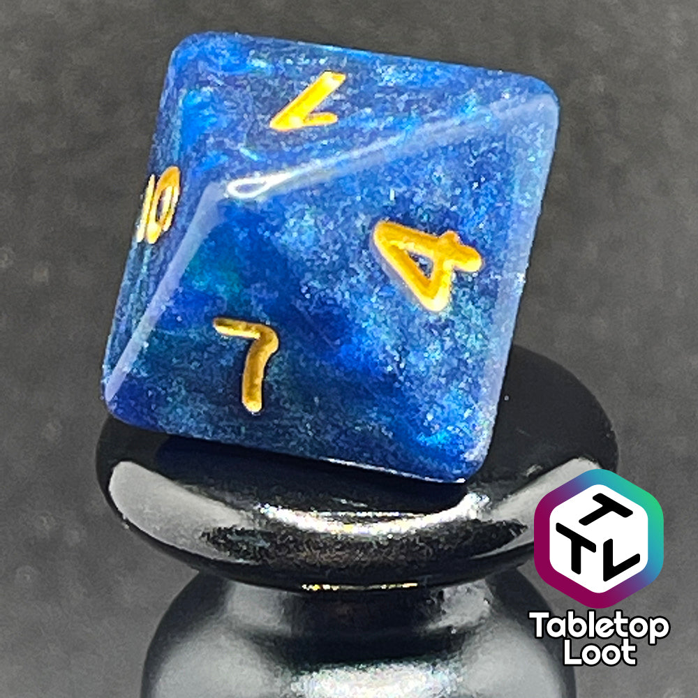 A close up of the D8 from the Neptune's Grace 7 piece dice set from Tabletop Loot with swirls of shimmery blue, hints of green , and gold numbering.