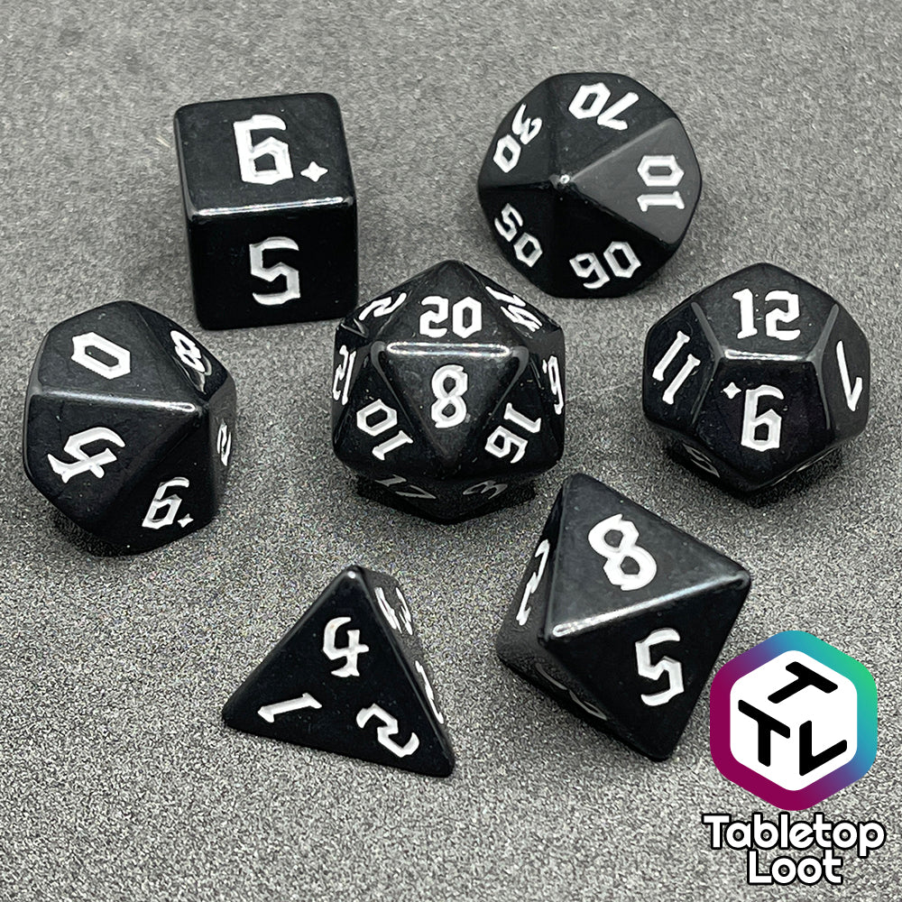 The Nevermore 7 piece dice set from Tabletop Loot with white gothic numbering on highly polished black faces.