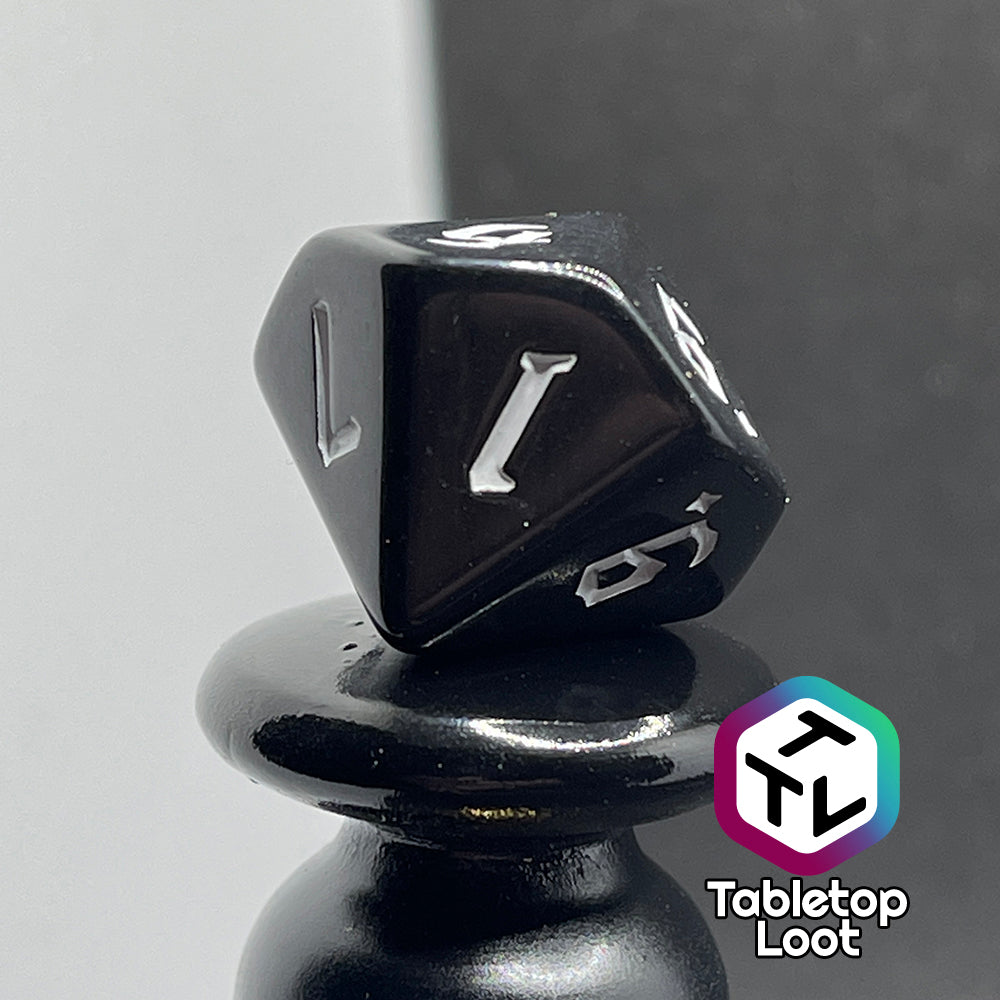 A close up of the D10 from the Nevermore 7 piece dice set from Tabletop Loot with white gothic numbering on highly polished black faces.