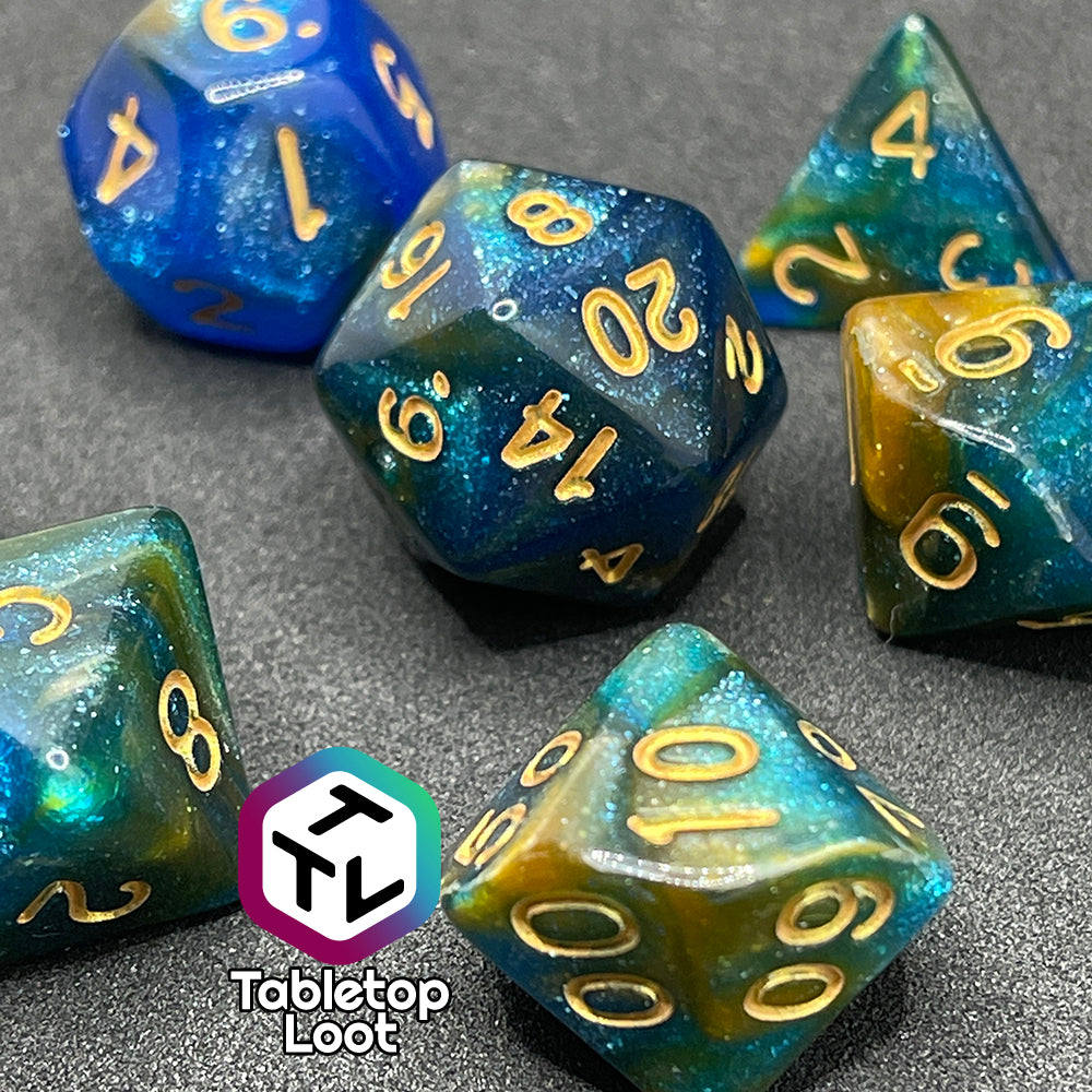 A close up of the Nimrodel 7 piece dice set from Tabletop Loot with swirls of glittering blue, green, and orange and golden numbering.