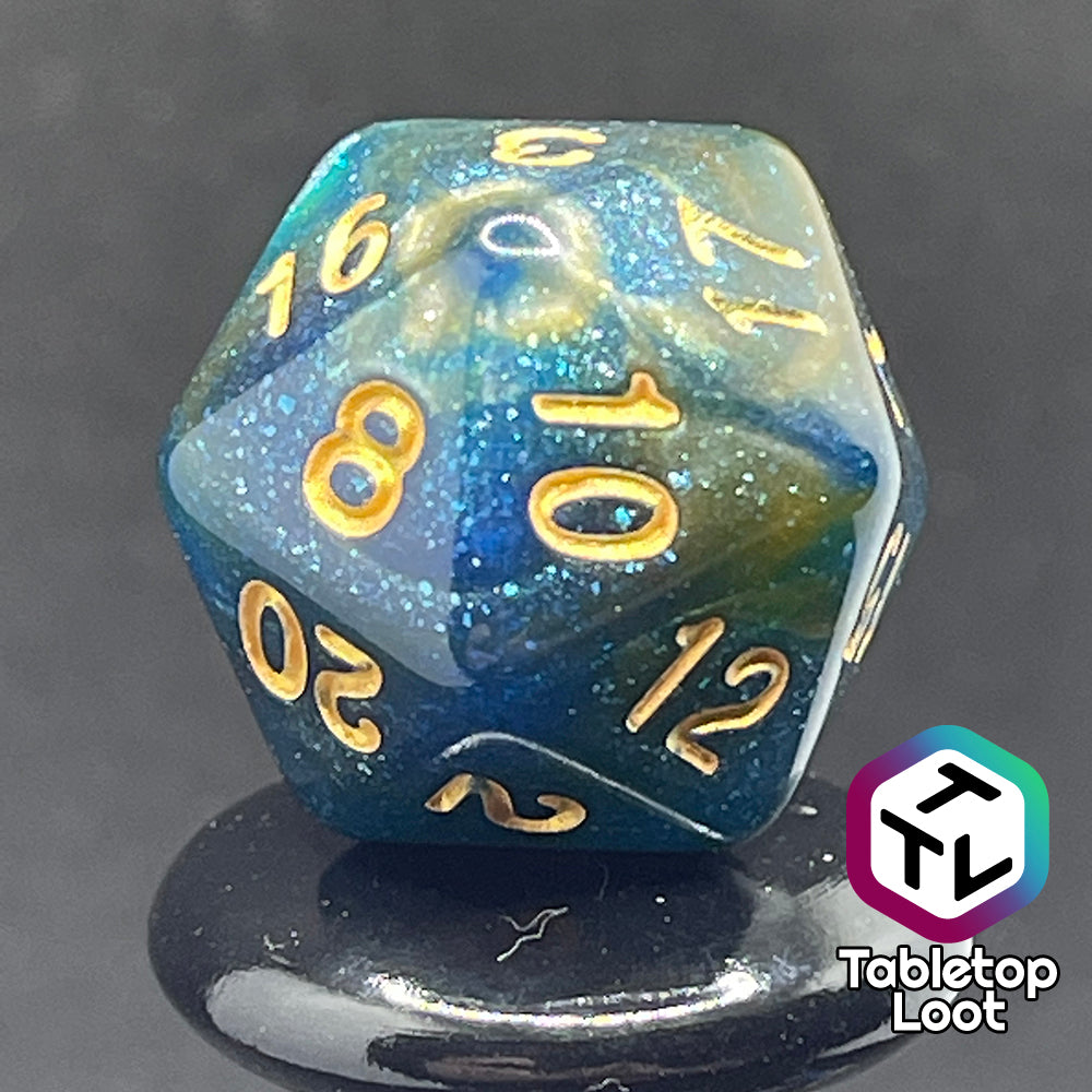 A close up of the D20 from the Nimrodel 7 piece dice set from Tabletop Loot with swirls of glittering blue, green, and orange and golden numbering.